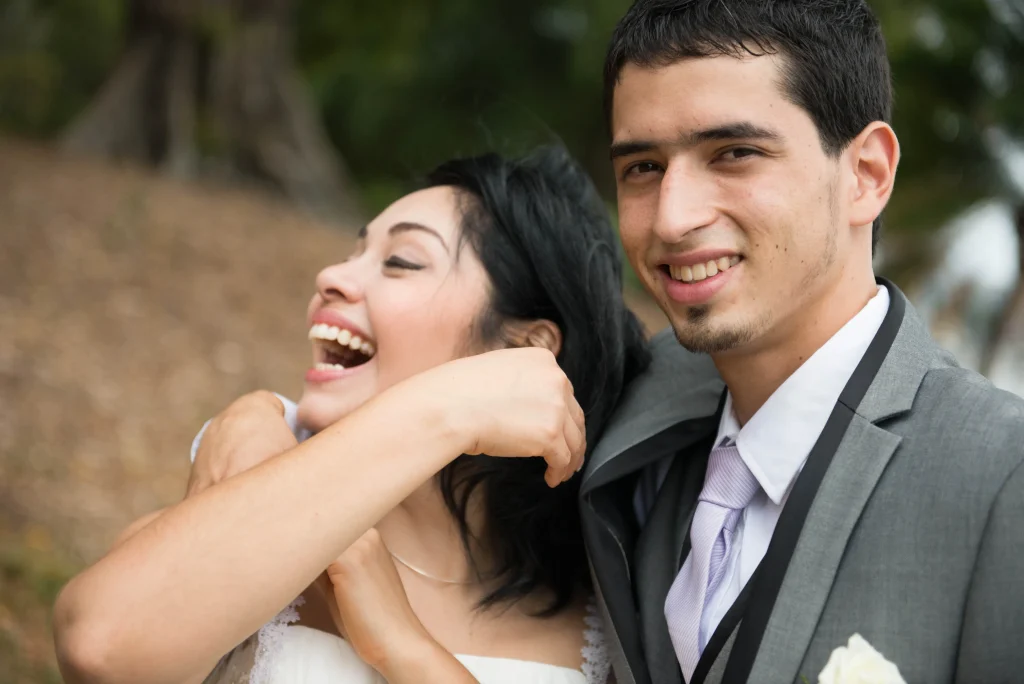 The bride laughs while embracing the groom outdoors.