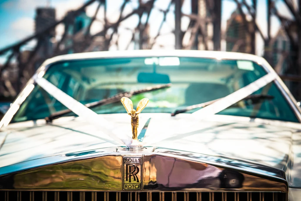The ribbon-decorated wedding car beneath the steelwork of a bridge.